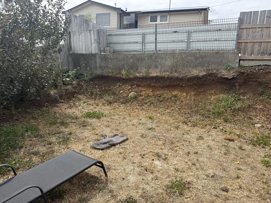 Before: dead lawn and an eroding, unretained slope below the neighbouring block