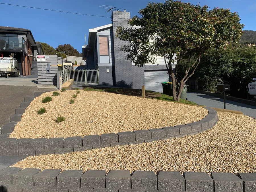 Block-edged curved gravel garden bed along a driveway