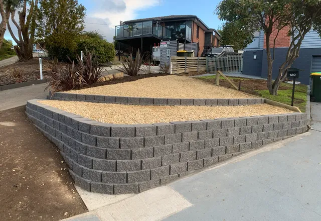 Curved block retaining wall holding a neat gravel terrace on a street frontage