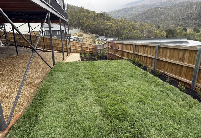 Fresh lawn and gravel path on a new-build block with mountain views behind