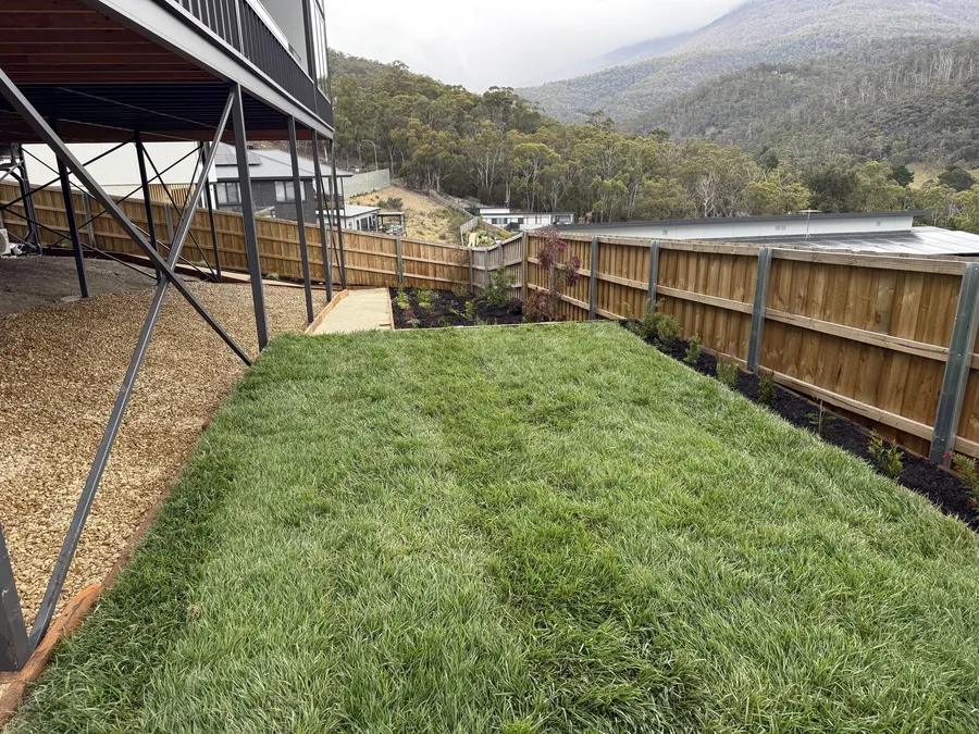 Fresh lawn beside a gravel path and new garden beds, looking out to the mountains