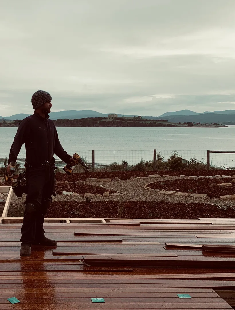 Robin standing on a newly built hardwood deck overlooking a waterfront garden