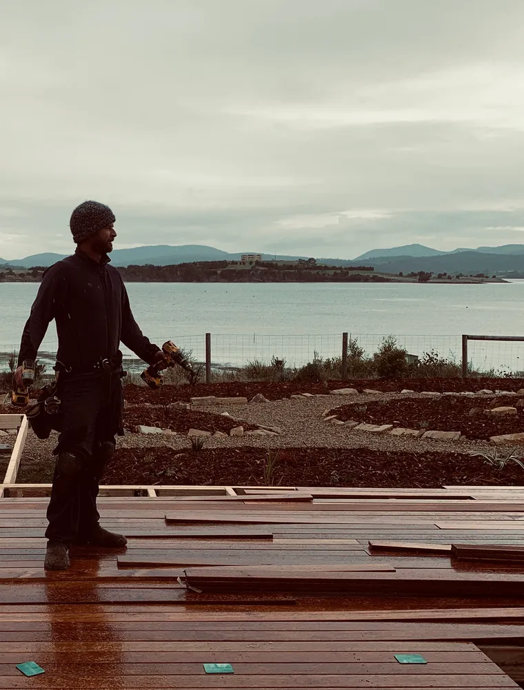 Robin standing on a newly built deck above a waterfront garden he landscaped