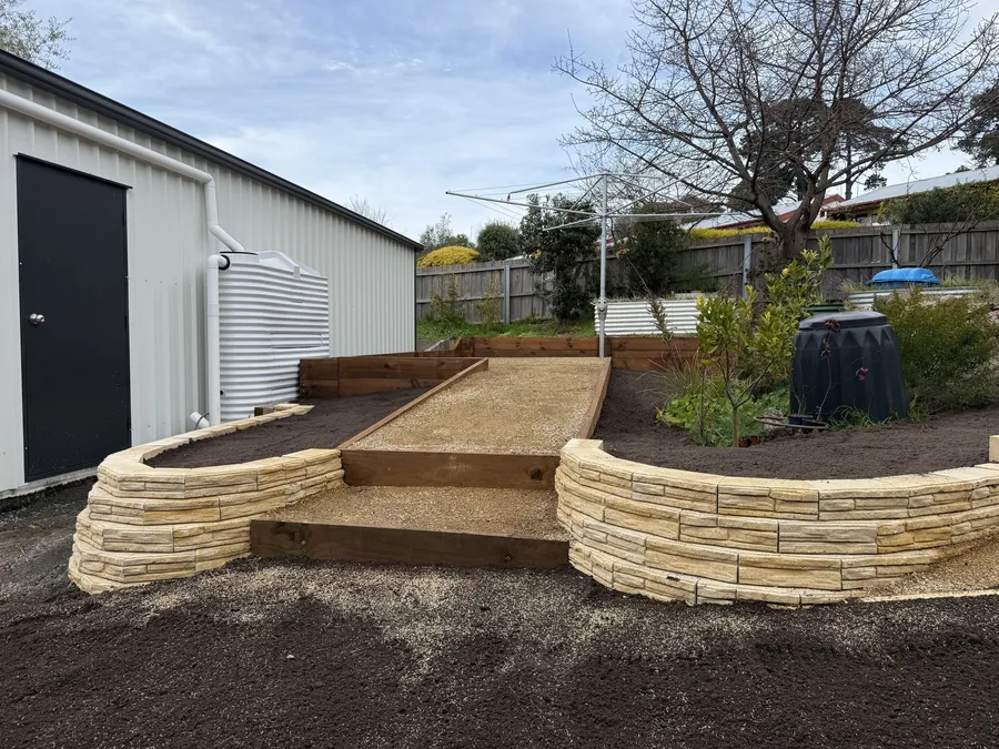 Curved sandstone raised beds flanking timber-edged gravel steps