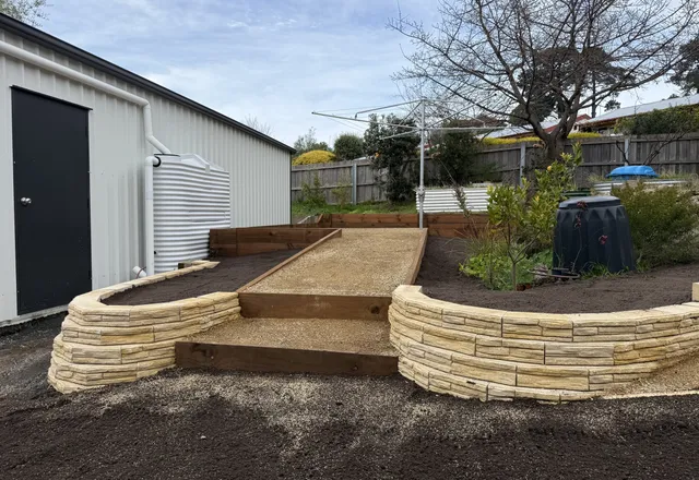 Curved sandstone block raised garden beds either side of timber-edged gravel steps
