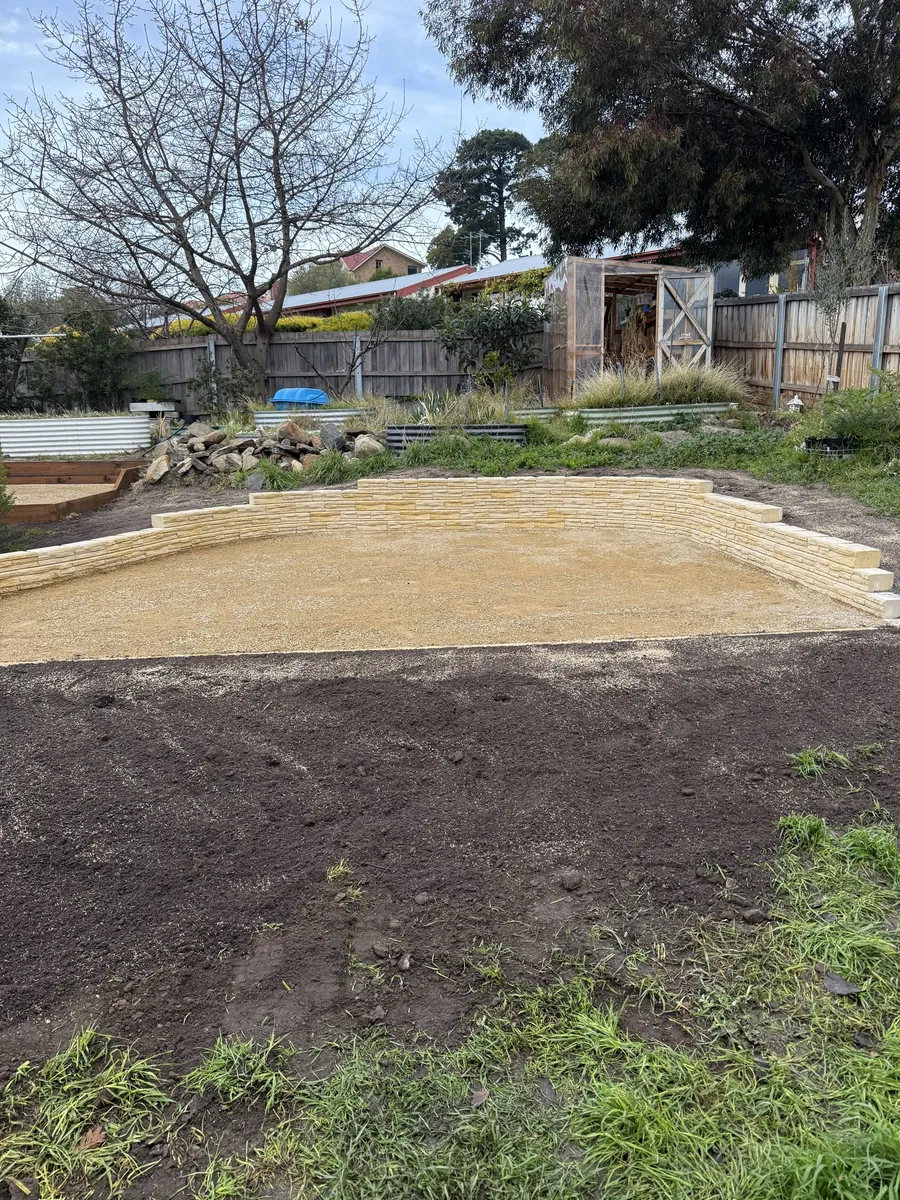 Low sandstone wall holding the levelled gravel pad ready for planting