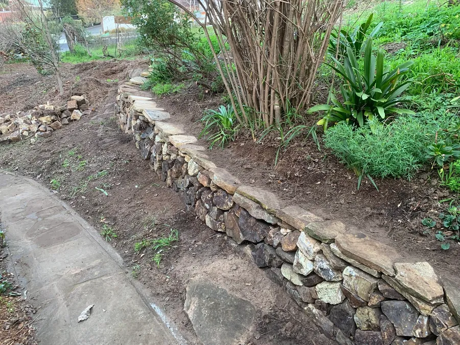 Low stone wall edging a garden bed beside a path