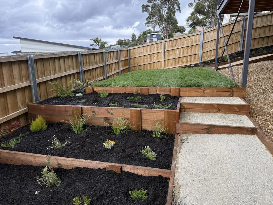 Timber-edged terraced garden beds stepping up to a new lawn