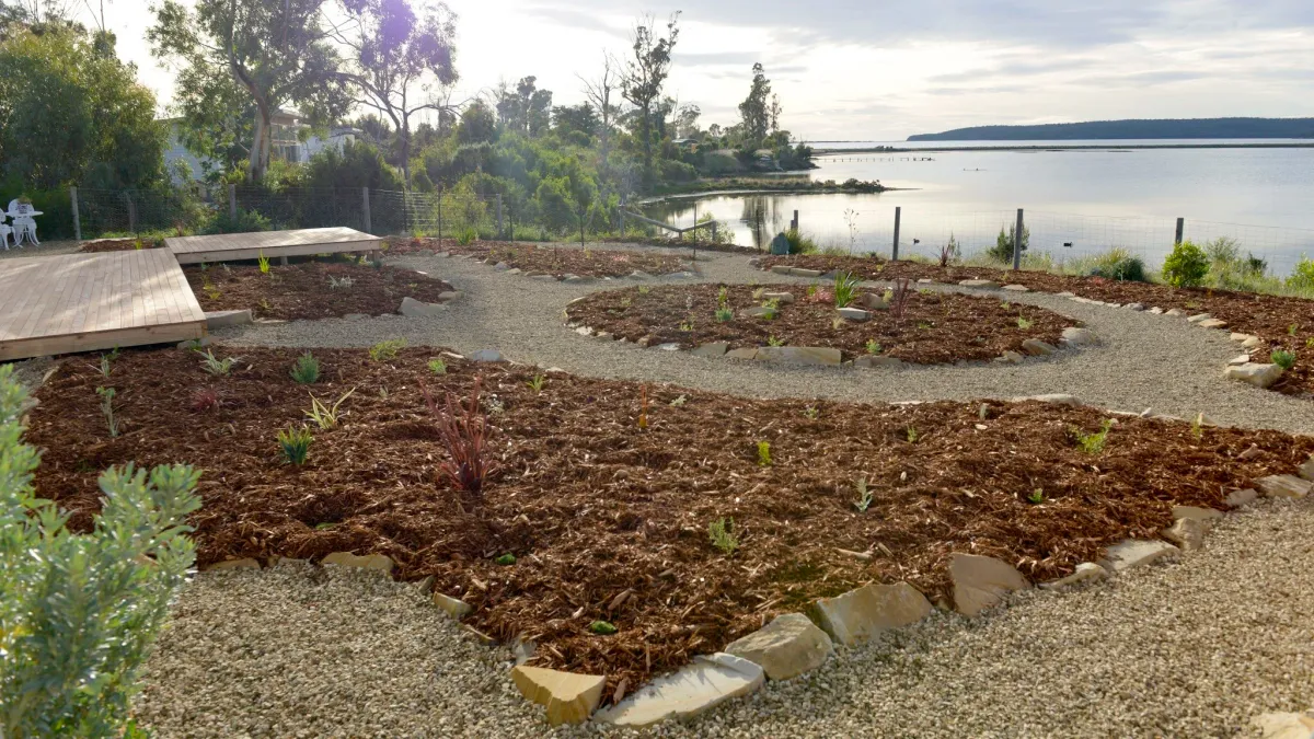 Freshly built circular garden beds with mulch and gravel paths